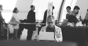 a man working at his laptop at the airport in black and white