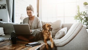 Woman sitting at home in front of laptop with dog